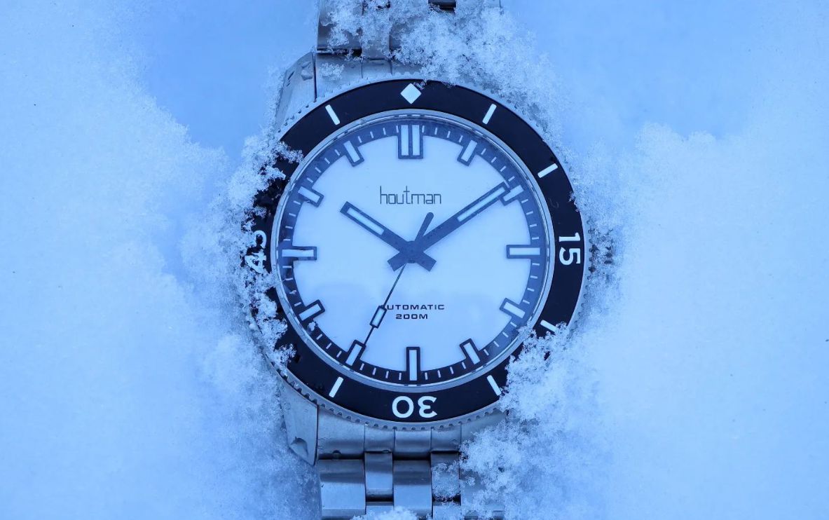 Premium matte white dial dive watch with matte black hands rests in the snow